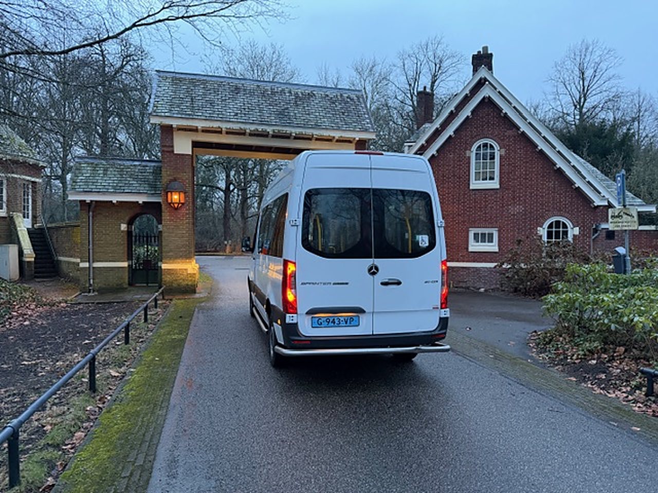 Rolstoelbus bij een landgoedpoort met rode baksteen
